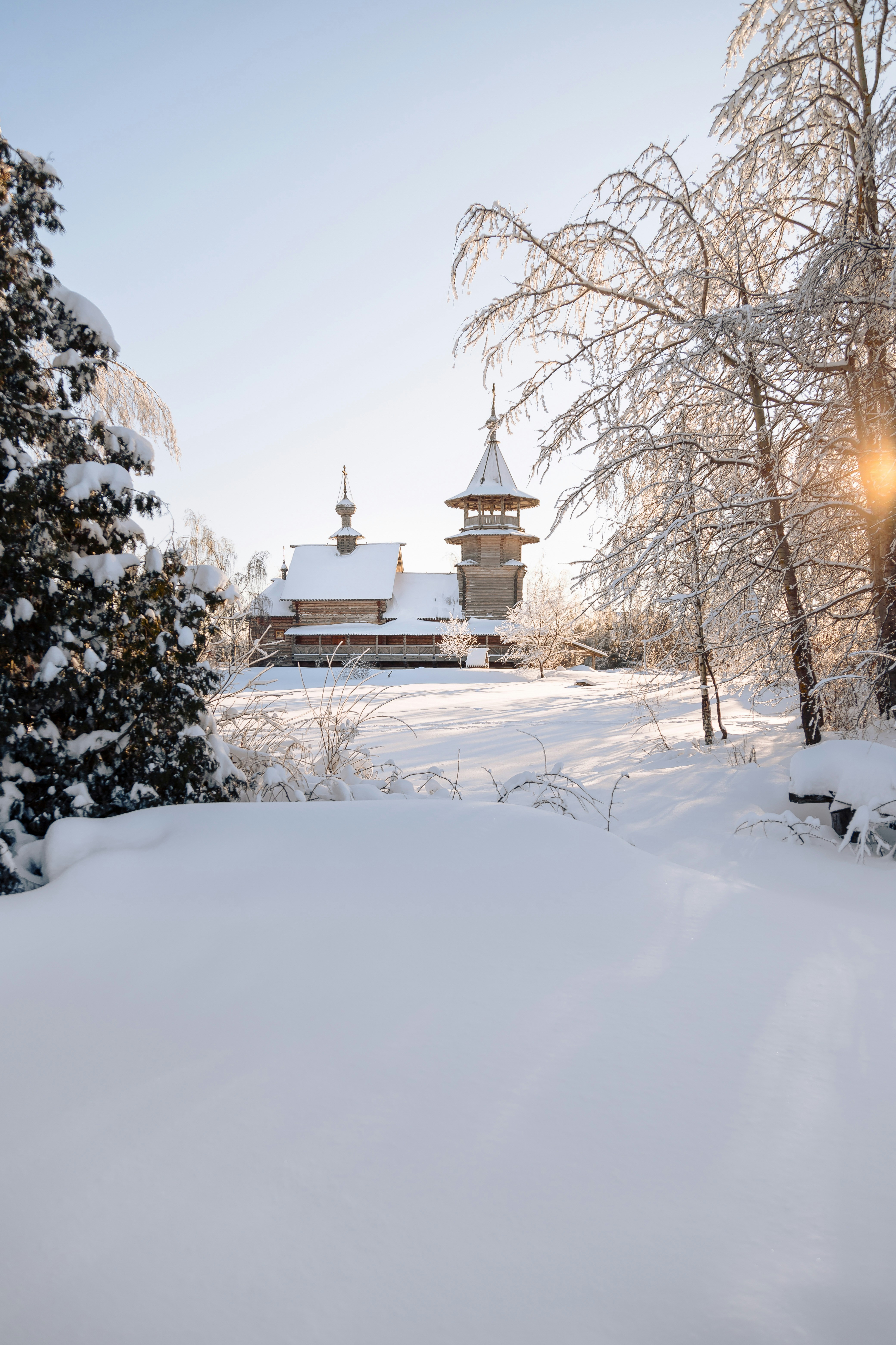 a snow covered field with trees and a building in the background