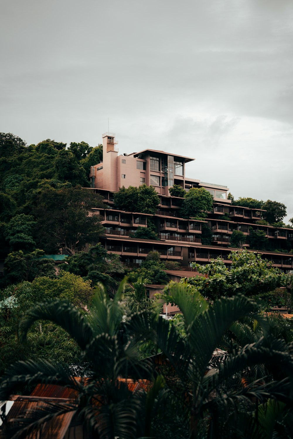 a pink building on a hill surrounded by trees