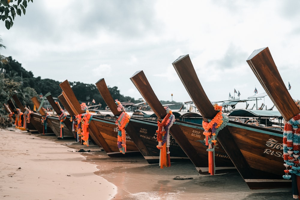 a row of boats sitting on top of a sandy beach