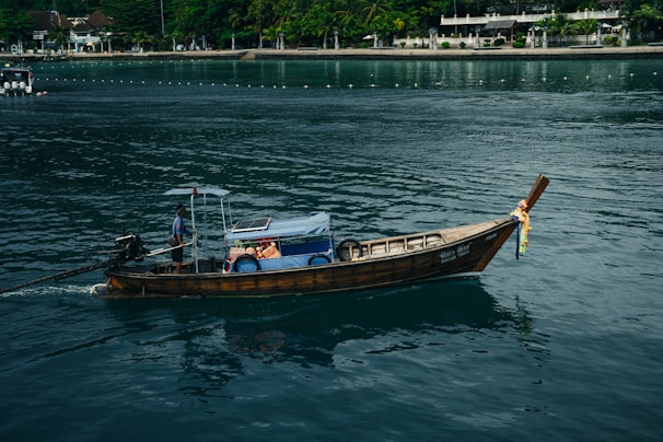 A traditional Maldivian boat gliding across the sparkling ocean near a lush island.