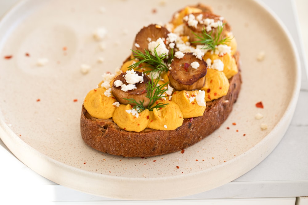 a white plate topped with a piece of bread covered in toppings