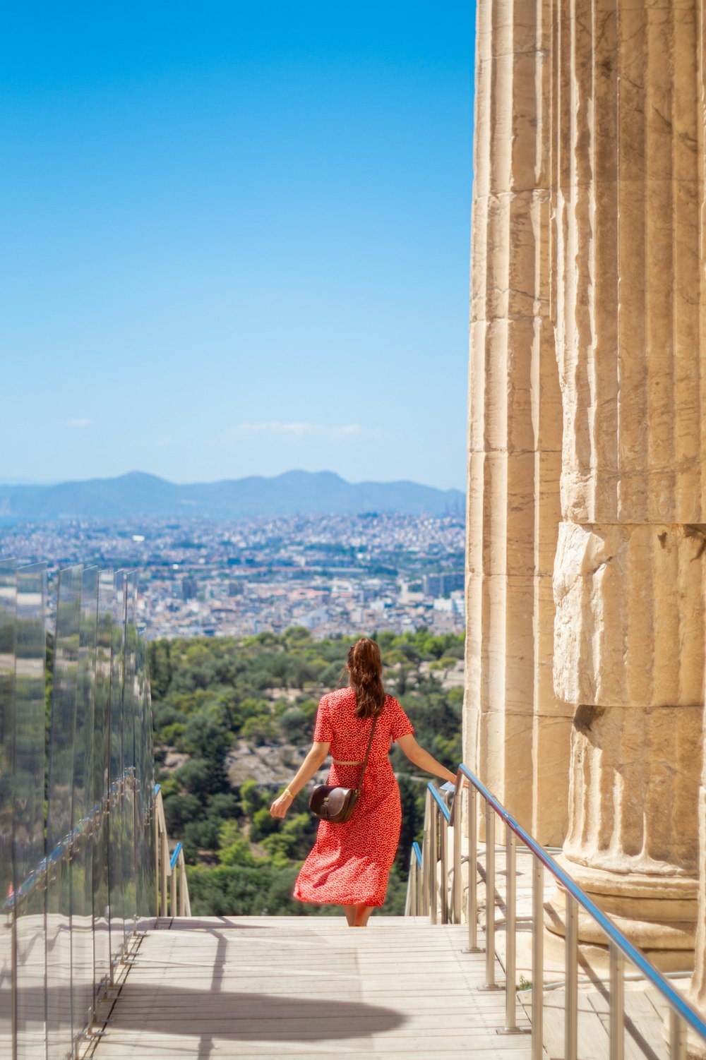 a woman in a red dress walking up a flight of stairs