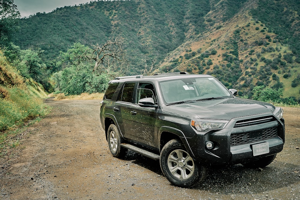 a black suv is parked on a dirt road