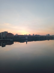 A calm sunrise over a city skyline with a microphone and headphones in the foreground.