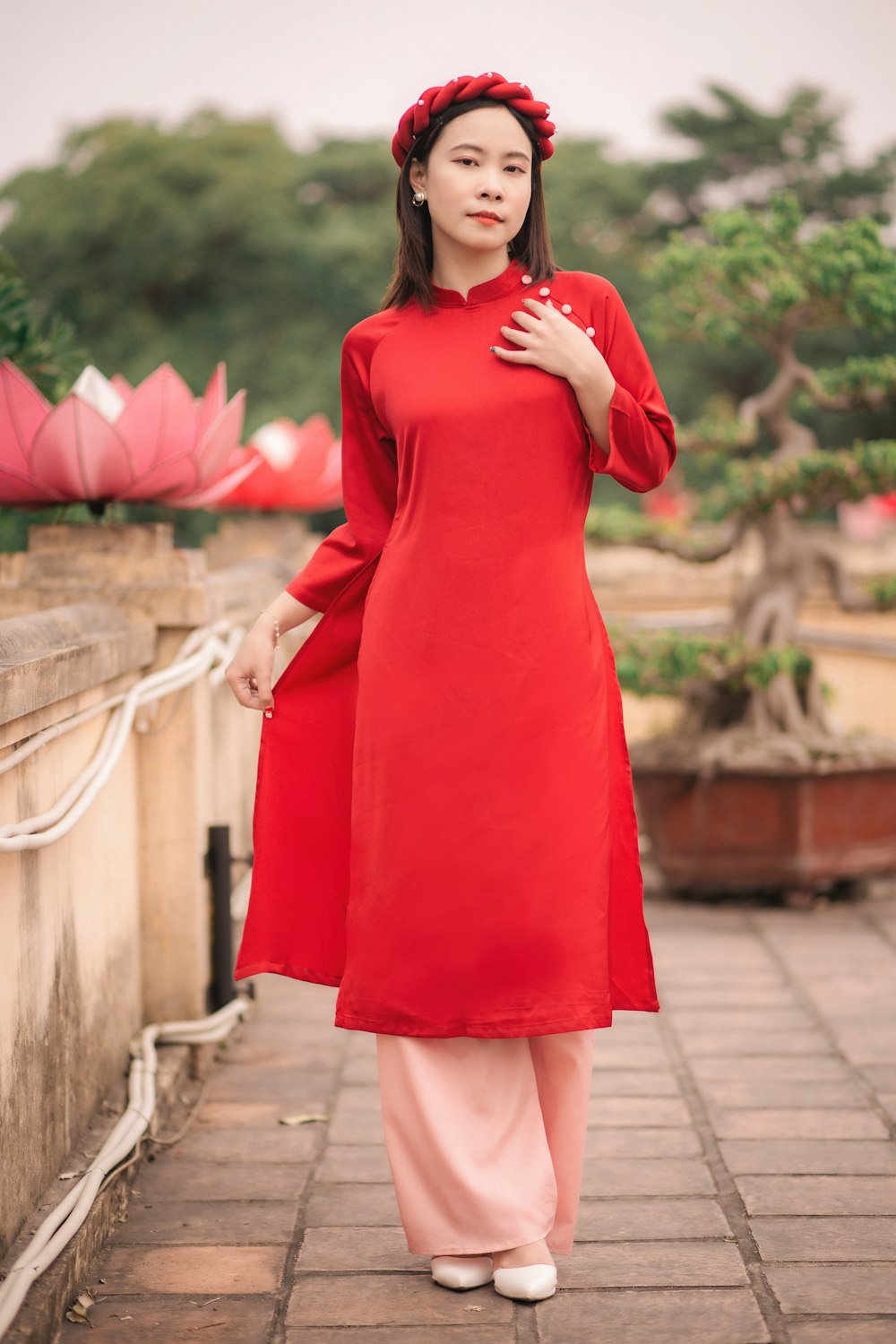 a woman in a red dress standing on a brick walkway