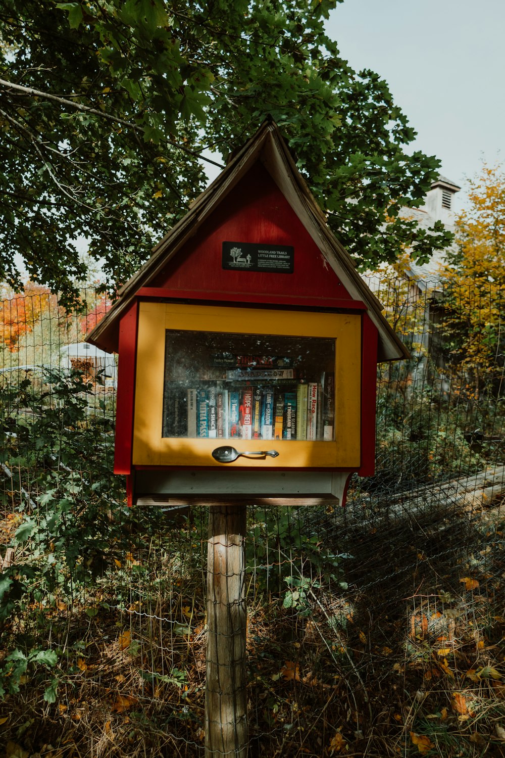 a red and yellow bird house with a picture of books on it