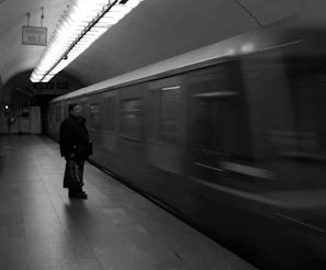 Black and white editorial shot of a local artist posing confidently on a subway platform