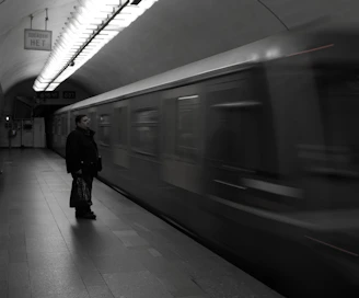 Black and white editorial shot of a local artist posing confidently on a subway platform