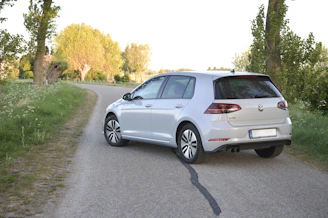 Side view of a dark blue hatchback on a countryside road