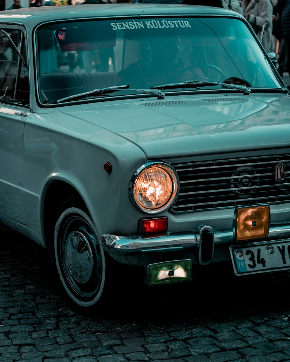 a blue car parked on a cobblestone street