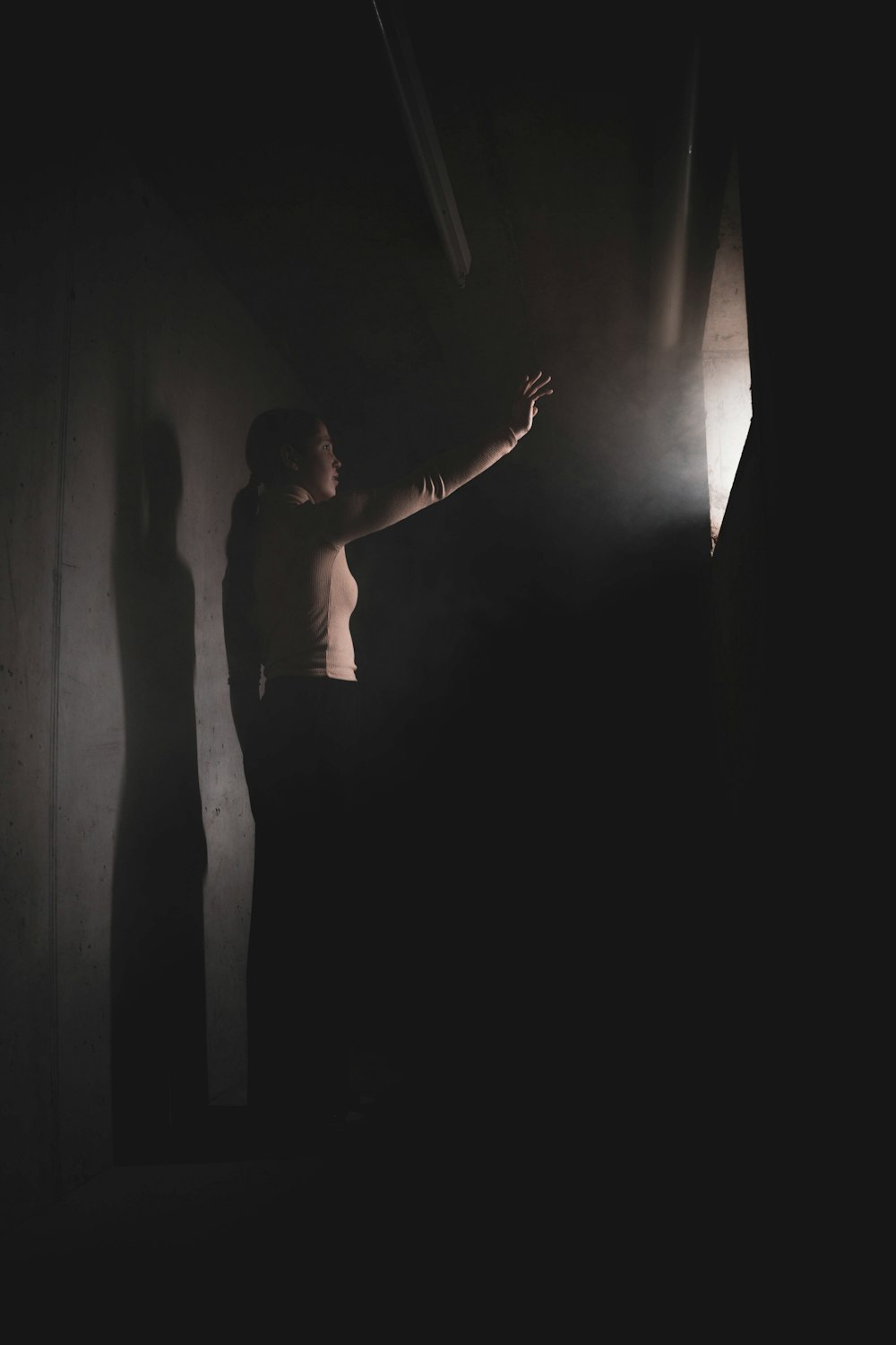 a woman standing in a dark room with her arms outstretched