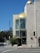 An urban street scene features a modern building with beige stone walls and a prominent golden dome at the top. There is an intersection with a traffic light, a hydrant, and a street sign labeled 'Westwood'. A menorah symbol is visible on the glass facade of the building.