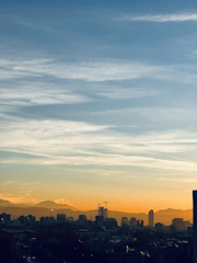 A Denver city skyline at sunset with financial graphs overlay.
