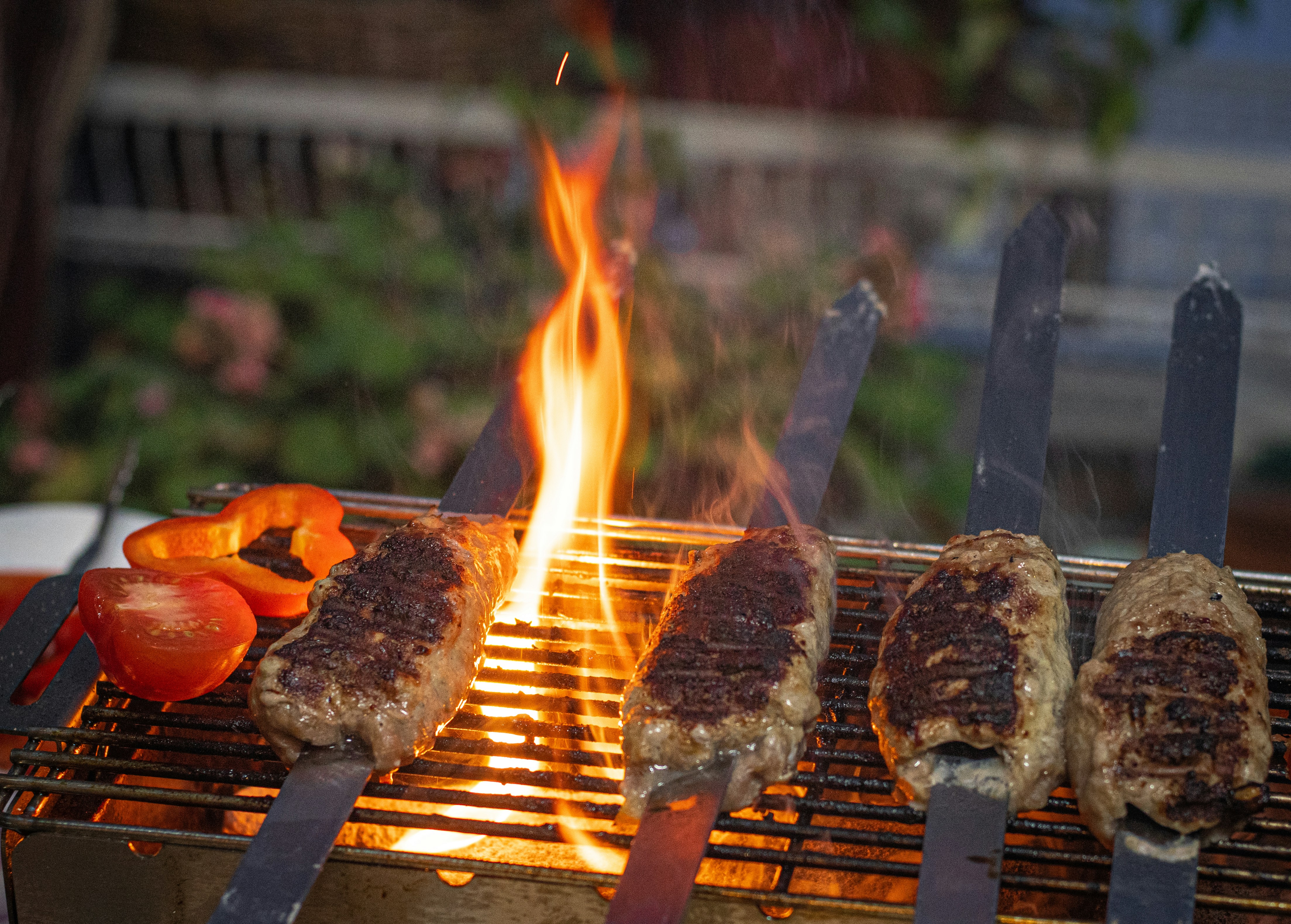 Bucătar pregătind kebab pe grătar, flăcări portocalii, atmosferă de restaurant nocturn