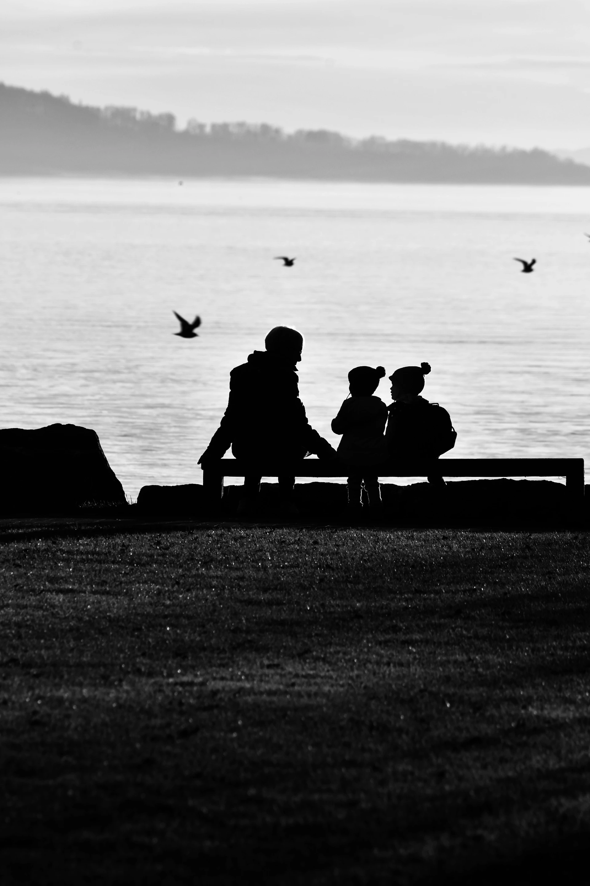a black and white photo of two people sitting on a bench