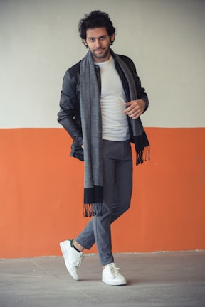 A man leaning against a brick wall, showcasing a versatile wearigoe outerwear piece with casual flair.