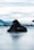 A pair of black sports shoes and a black bag with the brand name 'Bauer' are placed on an icy surface. The background features blurred mountains and a cloudy sky, creating a serene and somewhat cold atmosphere.