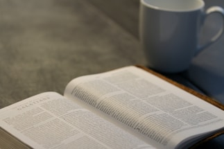 A serene workspace with a Bhagavad Gita open beside a laptop and a cup of tea.