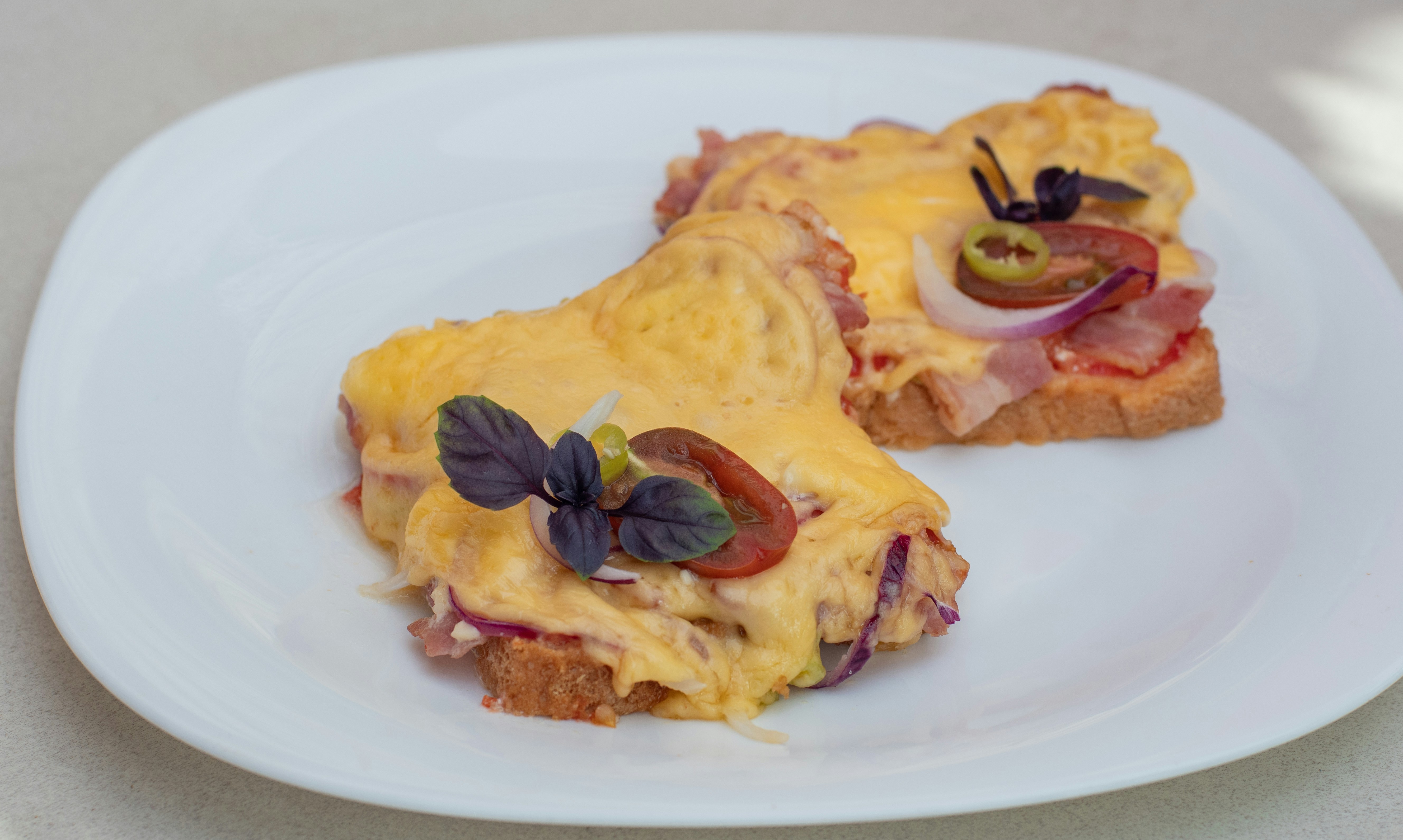 two pieces of bread with cheese and vegetables on them