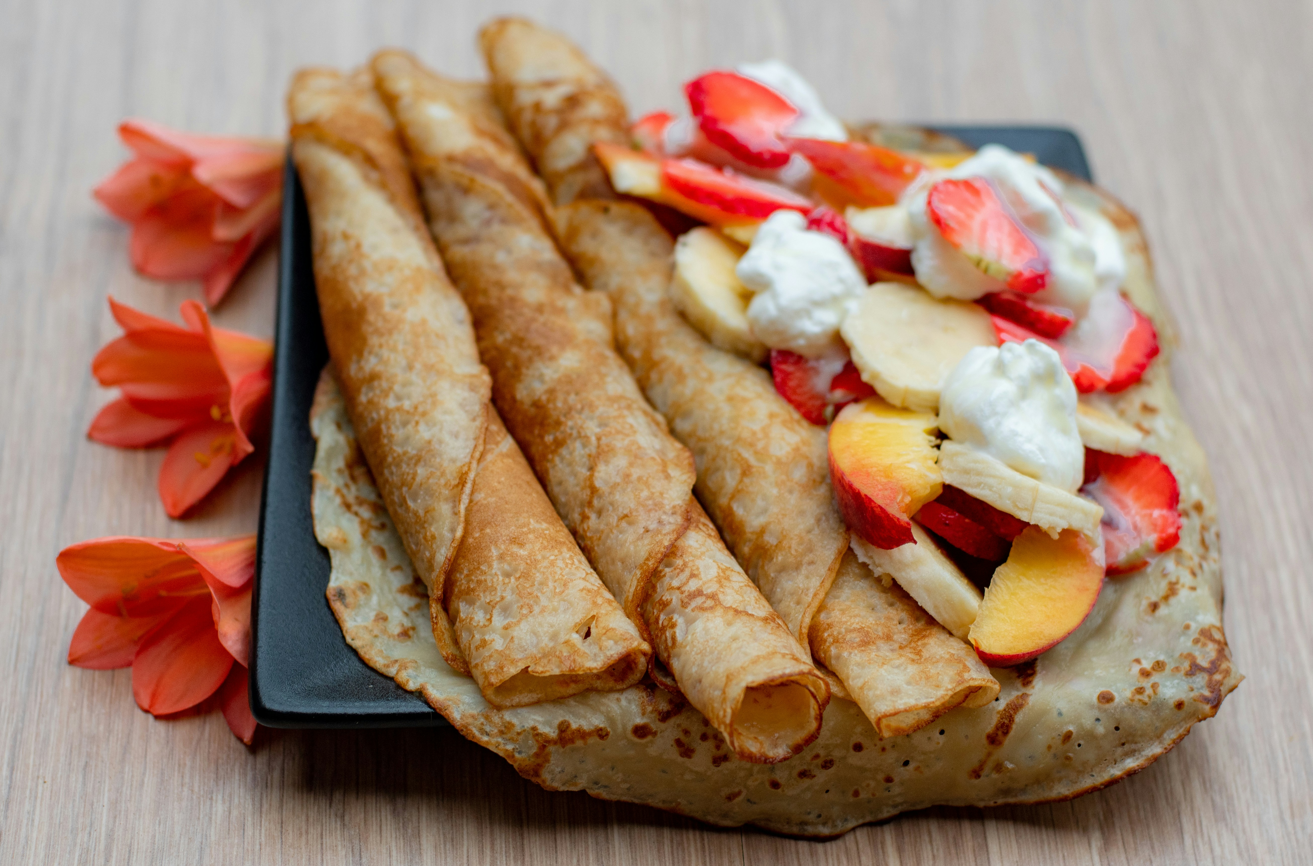 ein schwarzer Teller mit Crêpes und Obst