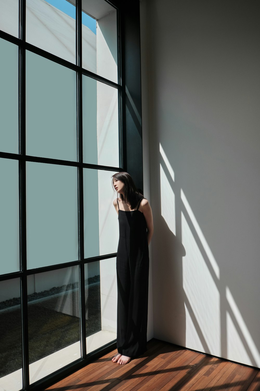 a woman leaning against a wall next to a window