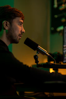 A male fasting coach recording a podcast in a minimalist studio setup with subtle orange lighting highlights