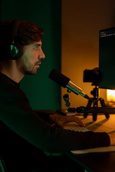 Voice artist working remotely with headphones and microphone in a cozy studio setting.