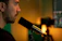 A confident young creator speaking into a microphone during a live online class.