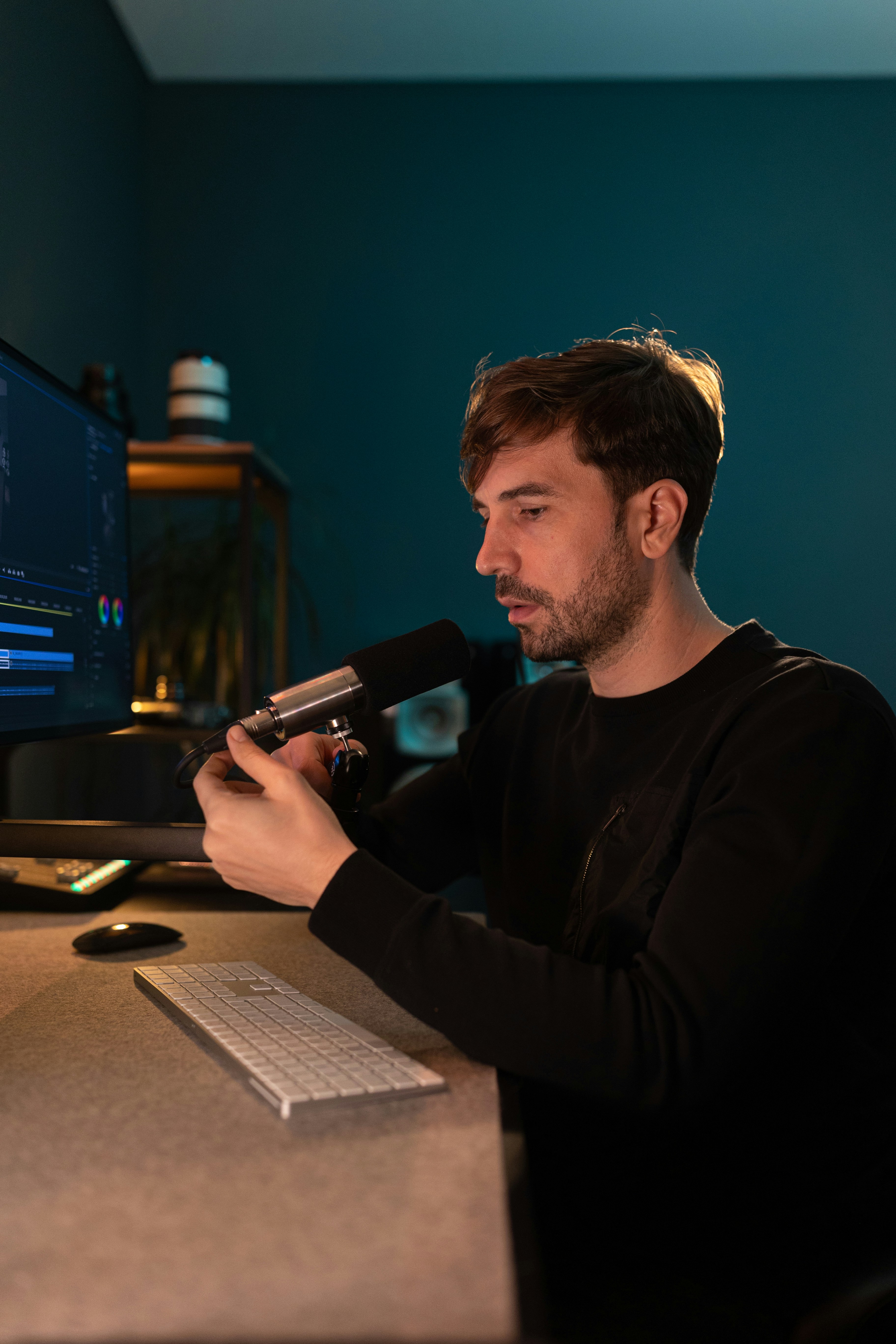 a man sitting in front of a computer holding a microphone