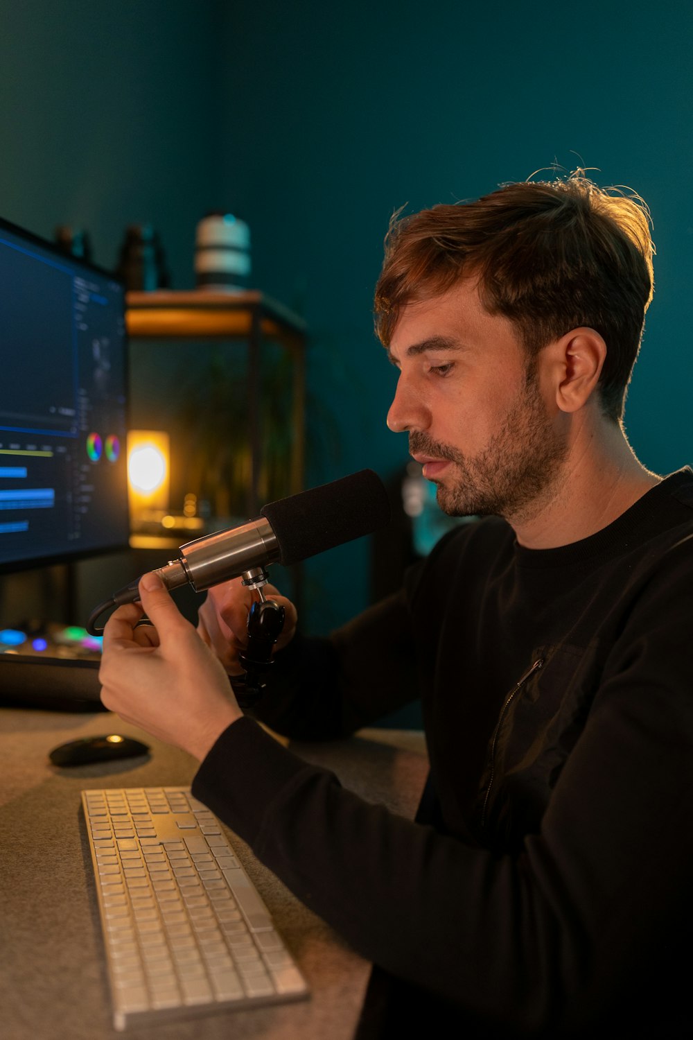 a man sitting in front of a computer holding a microphone