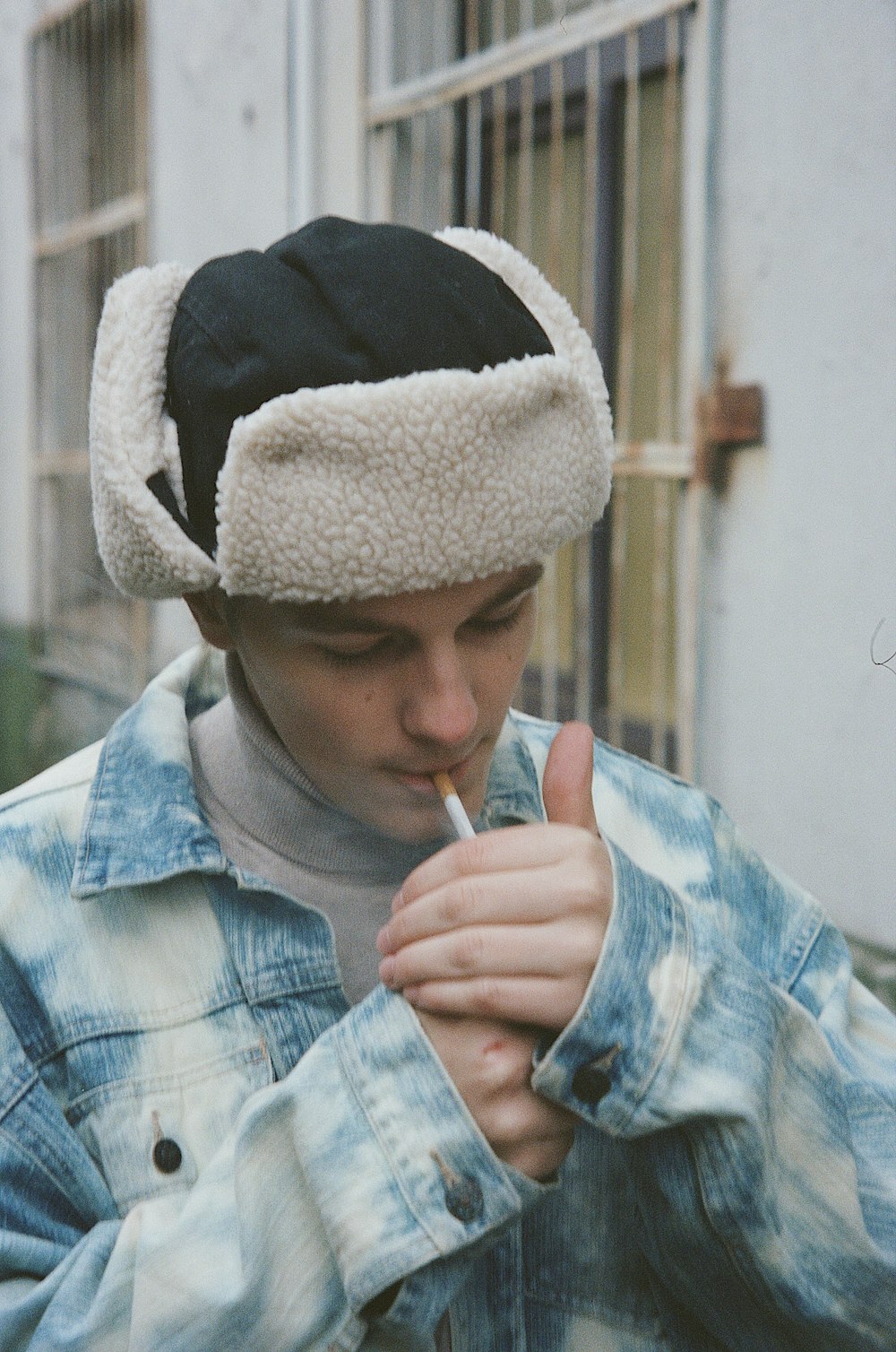 a young man smoking a cigarette wearing a hat