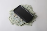 a cell phone sitting on top of a pile of money