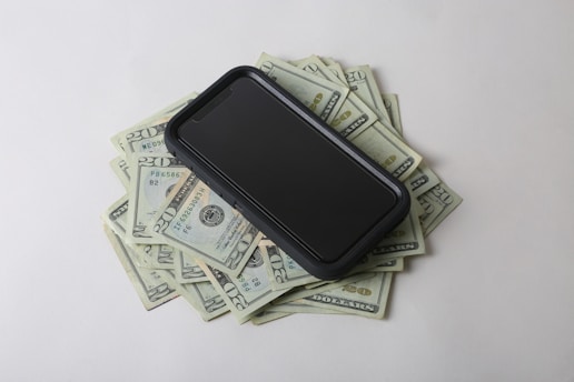 Close-up of hands counting money next to a laptop and smartphone.