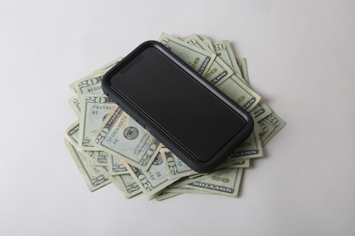 a cell phone sitting on top of a pile of money