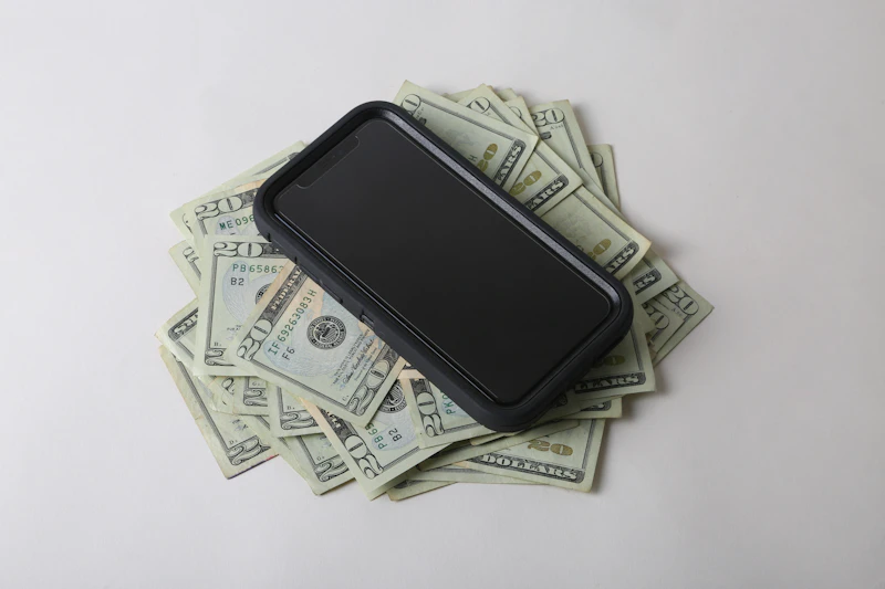 A phone resting on top of stacked banknotes.
