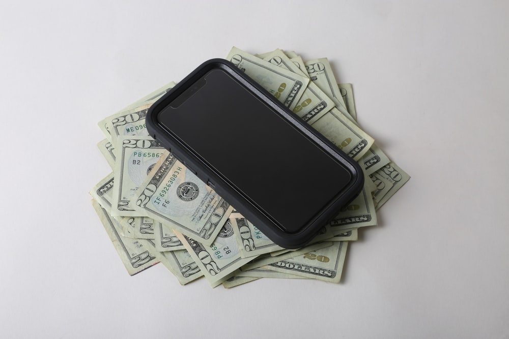 a cell phone sitting on top of a pile of money