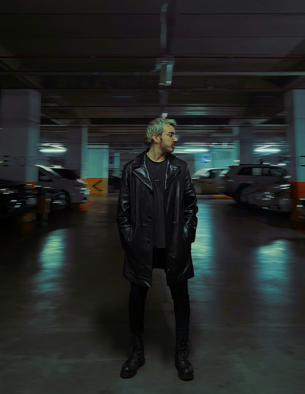 a man standing in a parking garage wearing a black coat