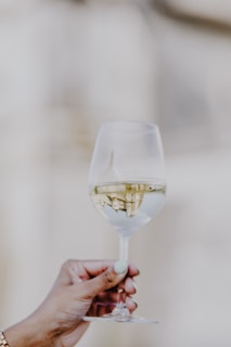 a person holding a wine glass with white wine in it