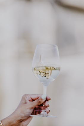 a person holding a wine glass with white wine in it