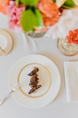 a white plate topped with food next to a vase of flowers