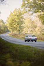 Group of classic 2CV cars driving through a picturesque countryside road.
