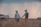 Young couple happily shaking hands with a terraviva agent near a plot of land.