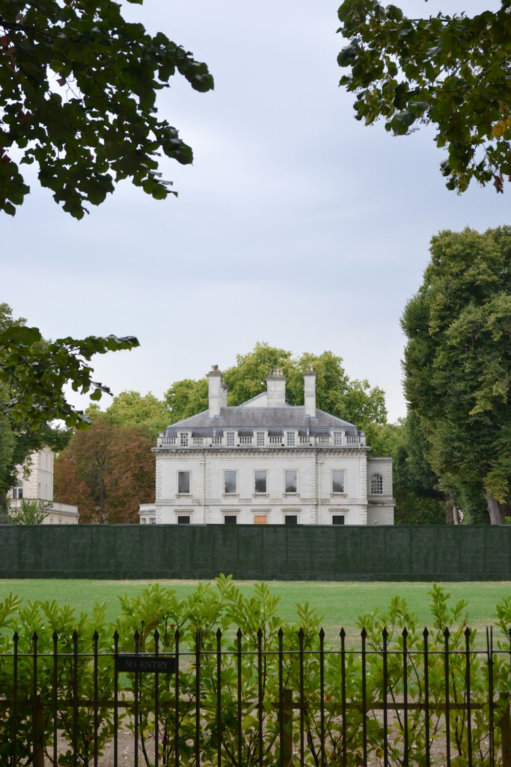 a large white house behind a black fence