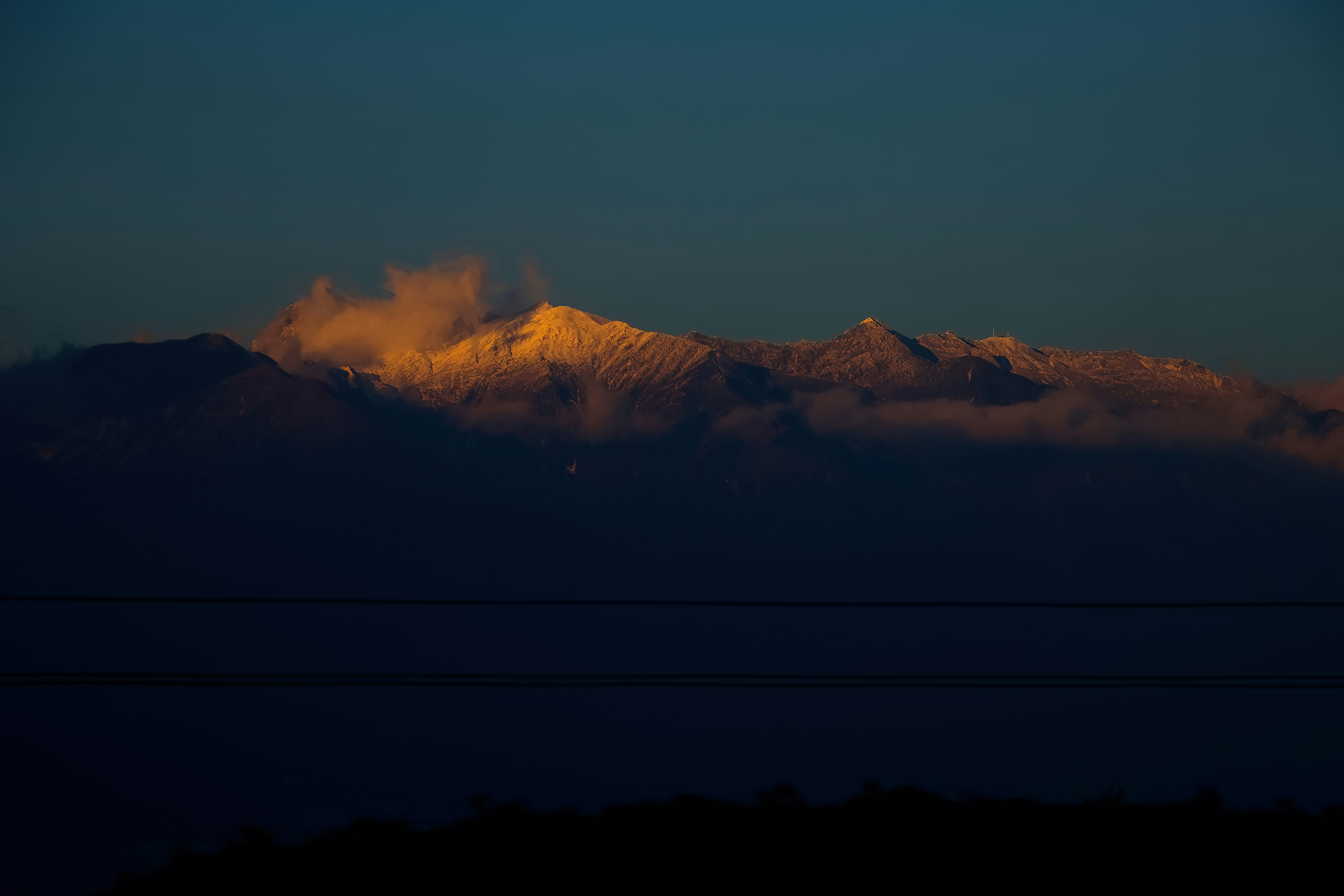a view of a mountain range with clouds in the foreground