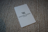 A white card with the Waldorf Astoria Las Vegas logo is placed on a textured, woven surface.