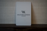 A light gray key card with the logo and text 'Waldorf Astoria Las Vegas' set against a textured woven background. The card appears minimalist and elegant.