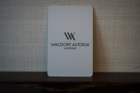 A light gray key card with the logo and text 'Waldorf Astoria Las Vegas' set against a textured woven background. The card appears minimalist and elegant.