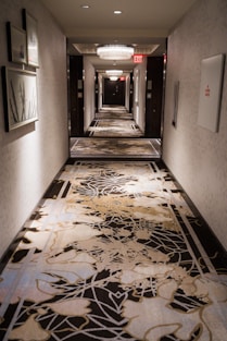 a long hallway with a black and white carpet and pictures on the wall