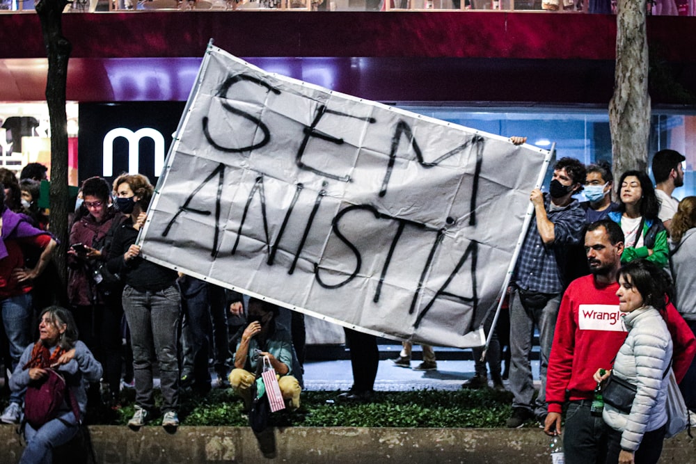 a group of people standing on a sidewalk holding a sign