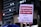 A poster is being held up at a protest. It contains Portuguese text advocating for democracy and rejecting amnesty. The background shows a cityscape with lit buildings and a traffic light.